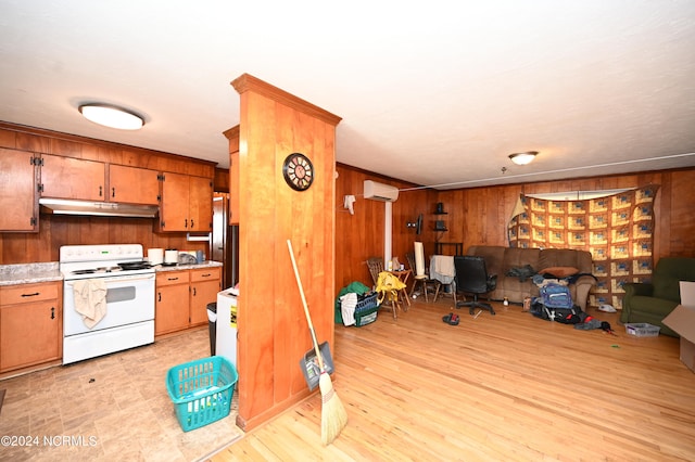 kitchen featuring stainless steel refrigerator, an AC wall unit, white electric range, light hardwood / wood-style flooring, and wooden walls