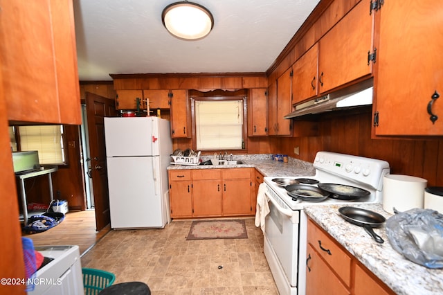 kitchen with ornamental molding, white appliances, wooden walls, and sink