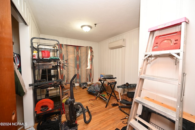 workout room featuring an AC wall unit, wood-type flooring, and a textured ceiling