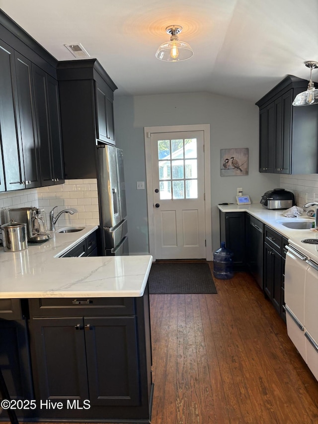 kitchen with sink, decorative backsplash, stainless steel fridge, and kitchen peninsula