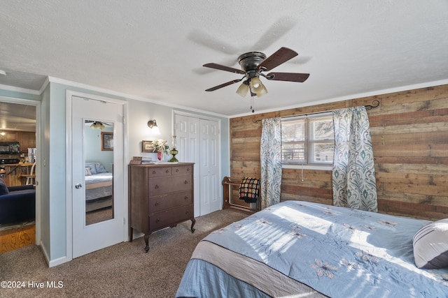 carpeted bedroom with wood walls, a closet, ceiling fan, and a textured ceiling