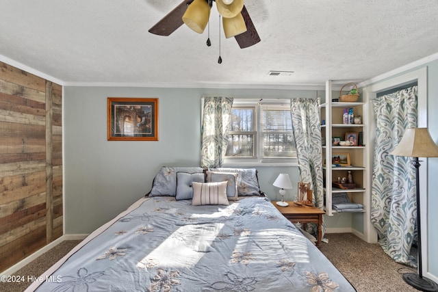 bedroom featuring ceiling fan, wooden walls, carpet, and a textured ceiling