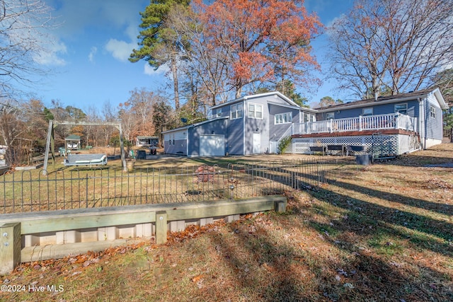 rear view of house with a yard, a garage, an outdoor structure, and a deck