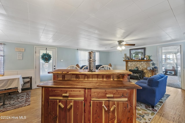 kitchen with a wood stove, ceiling fan, crown molding, and light hardwood / wood-style floors