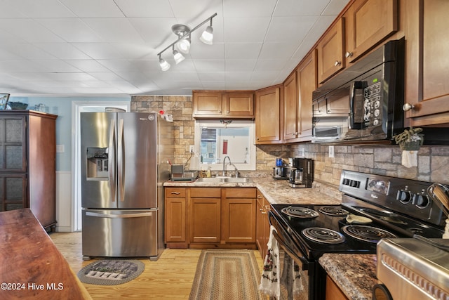 kitchen featuring light stone countertops, sink, decorative backsplash, appliances with stainless steel finishes, and light wood-type flooring