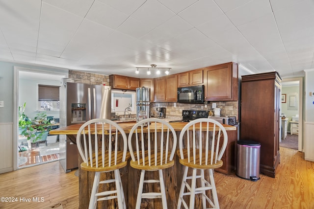 kitchen featuring black appliances, decorative backsplash, light hardwood / wood-style floors, and sink