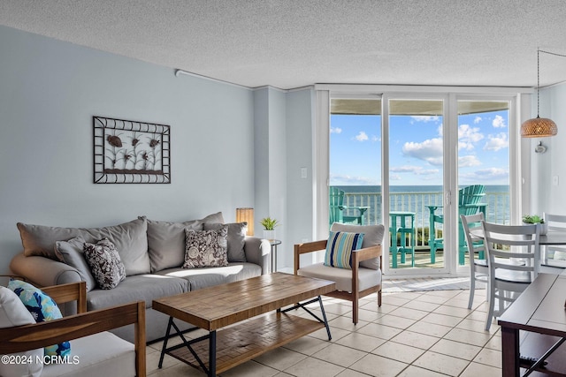 tiled living room featuring expansive windows, a water view, and a textured ceiling