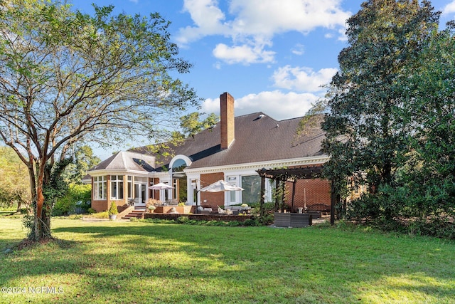 rear view of property with a lawn and a sunroom