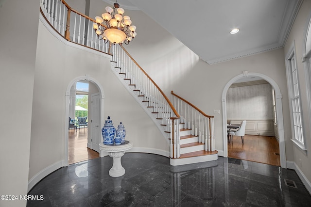 foyer with dark hardwood / wood-style floors, ornamental molding, a towering ceiling, and a chandelier