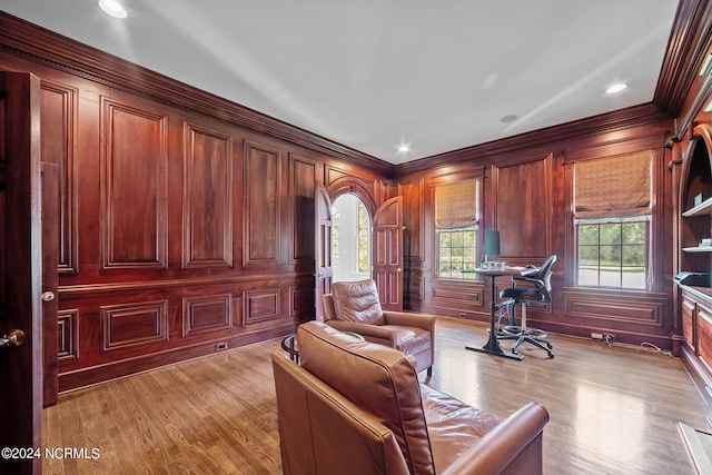 office with light hardwood / wood-style flooring, wooden walls, and crown molding