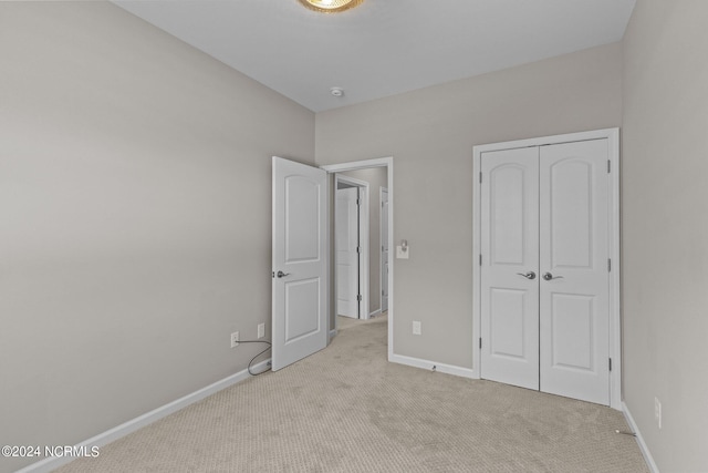 unfurnished bedroom with light colored carpet and a closet