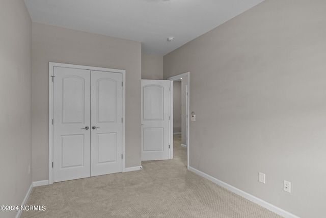 unfurnished bedroom with light carpet and a closet