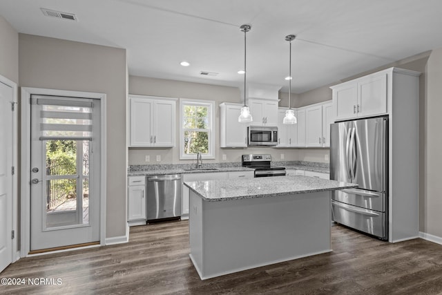 kitchen featuring appliances with stainless steel finishes, a kitchen island, sink, white cabinetry, and hanging light fixtures