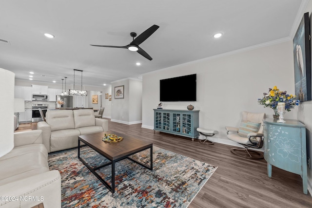 living room featuring ornamental molding, wood-type flooring, and ceiling fan with notable chandelier