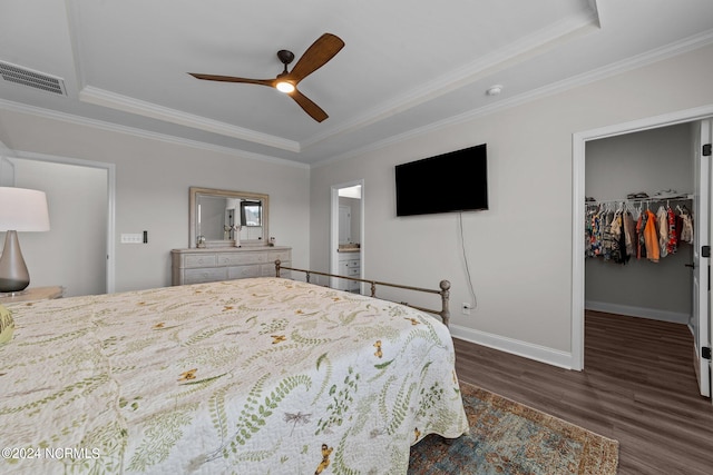 bedroom with ceiling fan, a spacious closet, crown molding, dark wood-type flooring, and a closet