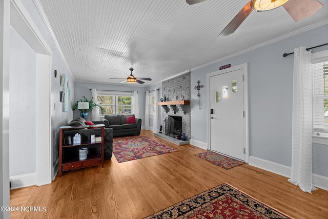 living room with wood-type flooring, crown molding, and a brick fireplace