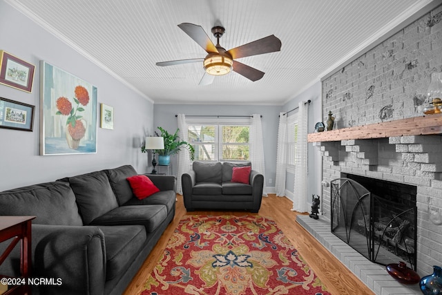 living room featuring light wood-type flooring, crown molding, and a fireplace