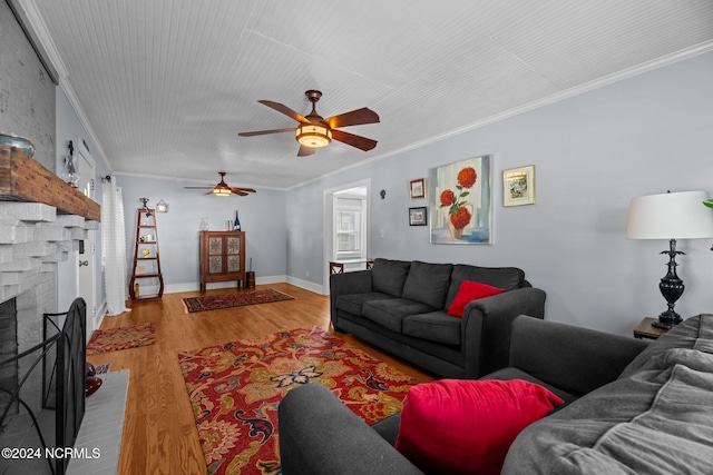 living room featuring ceiling fan, light wood-type flooring, a fireplace, and ornamental molding