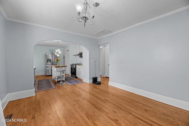 unfurnished dining area featuring light hardwood / wood-style flooring, a chandelier, a textured ceiling, and ornamental molding