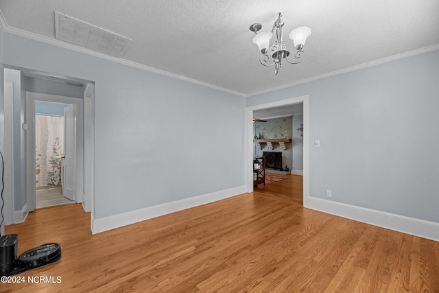 unfurnished dining area with a textured ceiling, crown molding, light hardwood / wood-style floors, and a notable chandelier