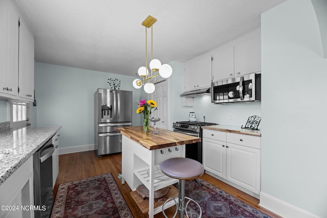 kitchen featuring white cabinets, hanging light fixtures, butcher block countertops, appliances with stainless steel finishes, and dark hardwood / wood-style flooring