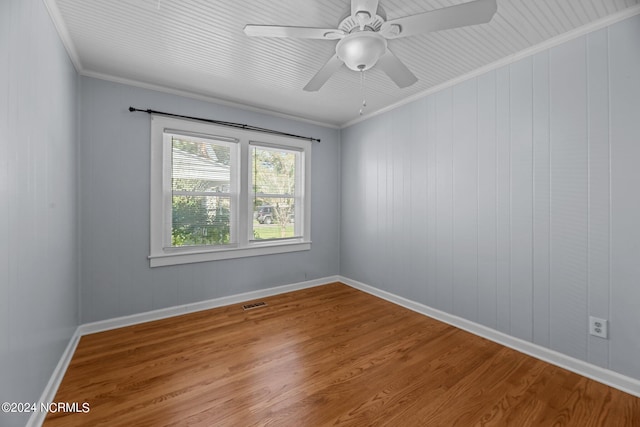 unfurnished room featuring ceiling fan, ornamental molding, wood walls, and hardwood / wood-style floors