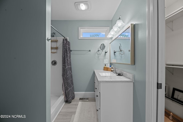 bathroom with walk in shower, vanity, and hardwood / wood-style flooring