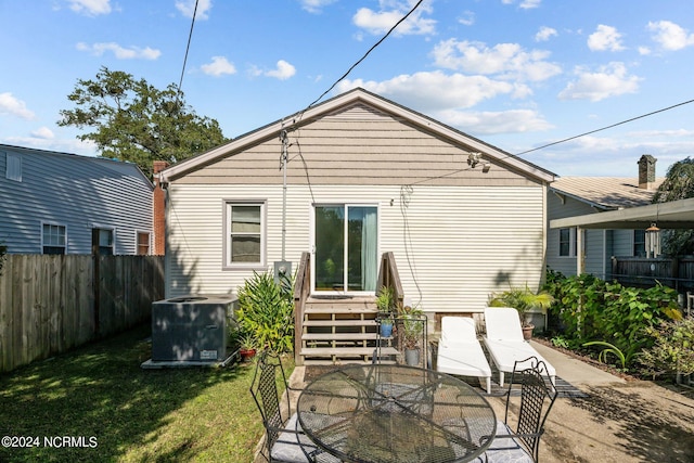 rear view of property with a lawn, cooling unit, and a patio