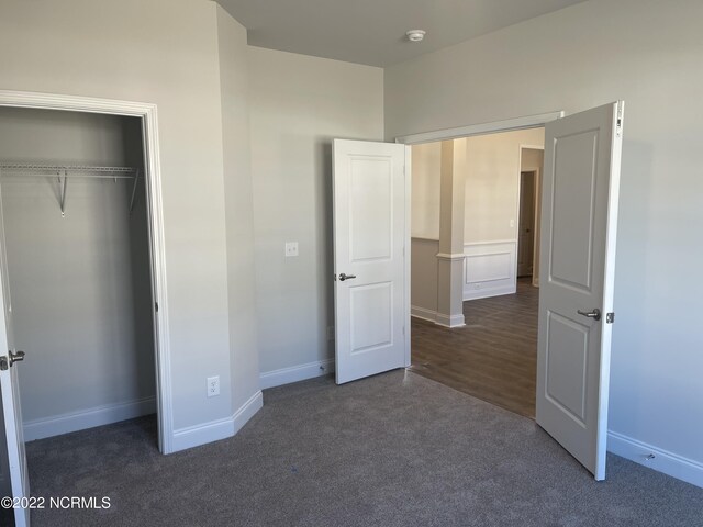 unfurnished bedroom featuring dark carpet and a closet