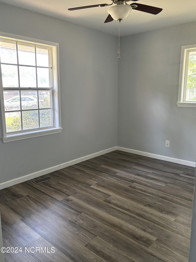 empty room featuring ceiling fan, a wealth of natural light, and dark hardwood / wood-style floors