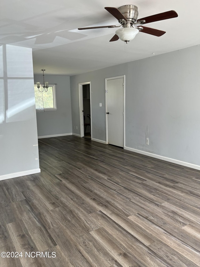 unfurnished room featuring dark wood-type flooring and ceiling fan with notable chandelier