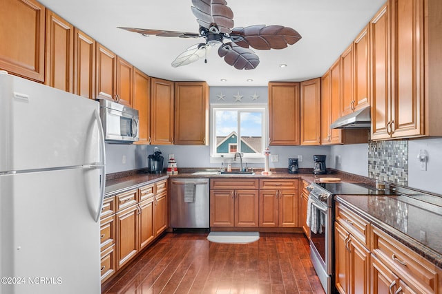 kitchen featuring ceiling fan, sink, dark wood-type flooring, stainless steel appliances, and dark stone counters