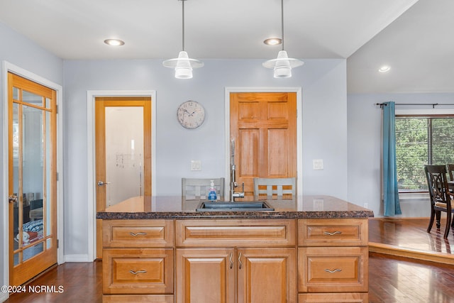 kitchen featuring dark stone counters, hanging light fixtures, and dark wood-type flooring