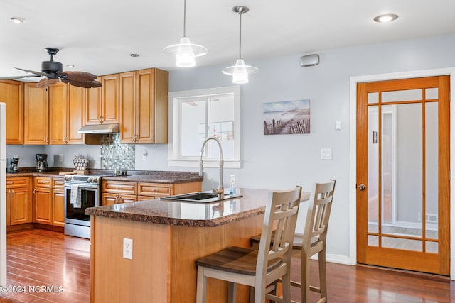 kitchen with sink, stainless steel range with electric stovetop, decorative light fixtures, dark wood-type flooring, and a breakfast bar