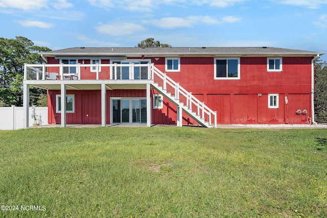 rear view of property with a balcony and a yard