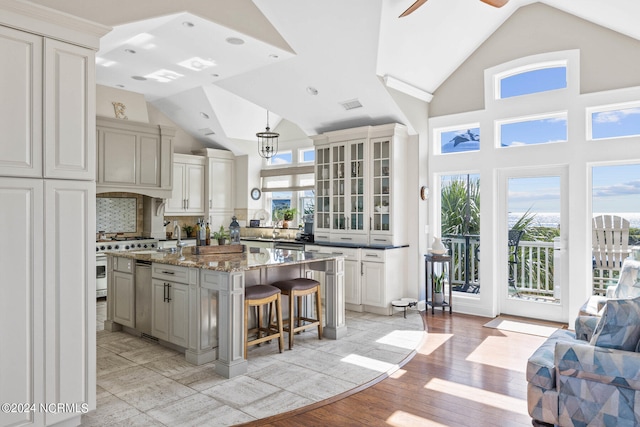 kitchen with a kitchen breakfast bar, light hardwood / wood-style floors, ceiling fan with notable chandelier, pendant lighting, and a center island