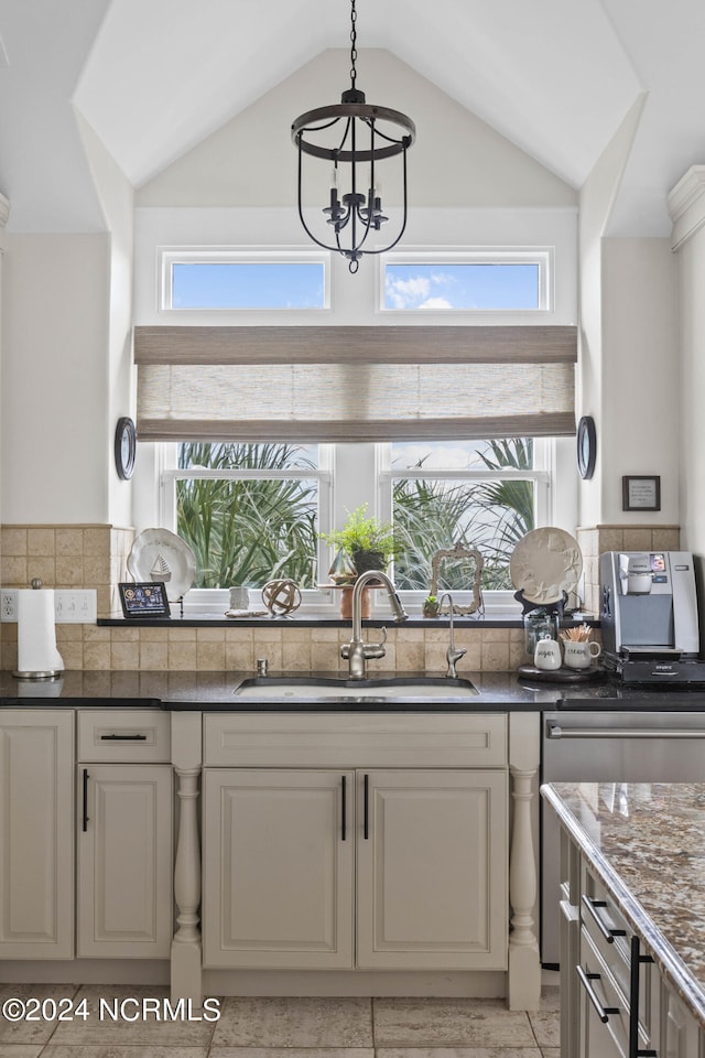 kitchen featuring vaulted ceiling, tasteful backsplash, pendant lighting, an inviting chandelier, and sink