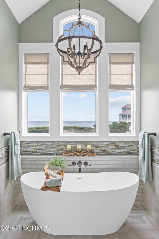 bathroom with a wealth of natural light, vaulted ceiling, and a bathing tub