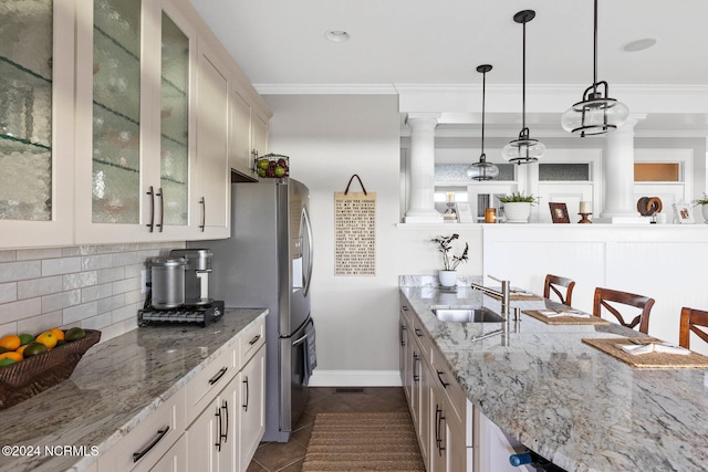 kitchen featuring light stone counters, tasteful backsplash, decorative light fixtures, sink, and stainless steel fridge with ice dispenser