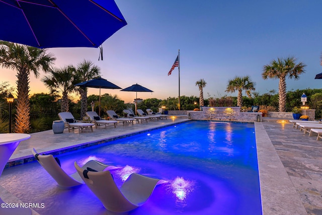 pool at dusk with a patio area