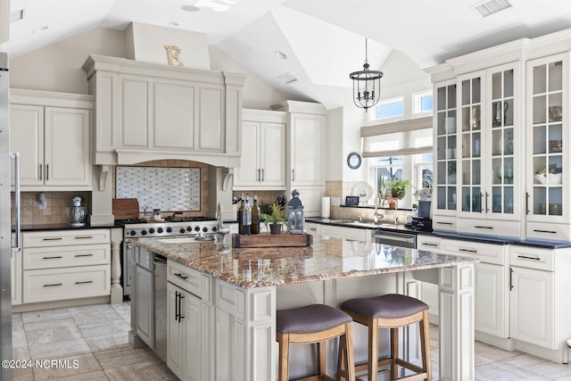 kitchen with dark stone counters, a kitchen island with sink, and tasteful backsplash