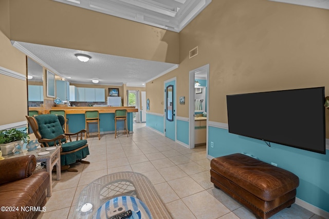 tiled living room featuring ornamental molding, a high ceiling, and a textured ceiling