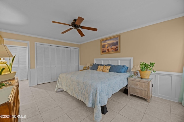 tiled bedroom featuring ornamental molding, multiple closets, and ceiling fan