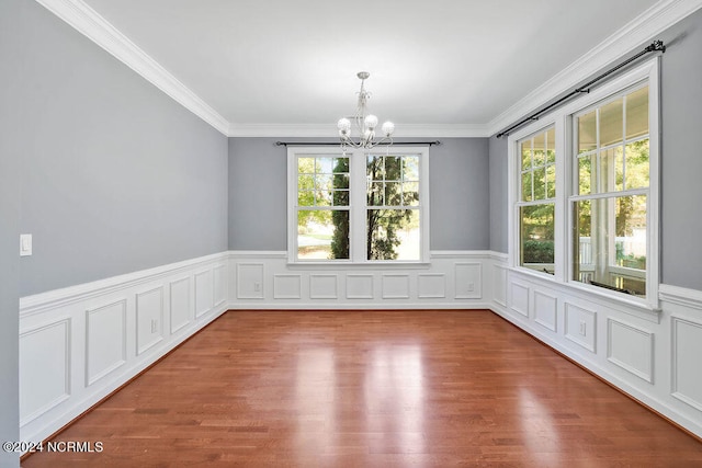 unfurnished dining area featuring a chandelier, hardwood / wood-style floors, and ornamental molding