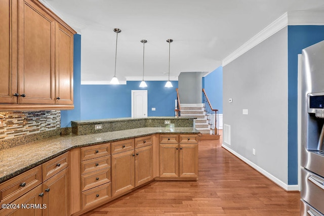 kitchen with crown molding, decorative light fixtures, dark stone countertops, stainless steel fridge with ice dispenser, and light hardwood / wood-style floors