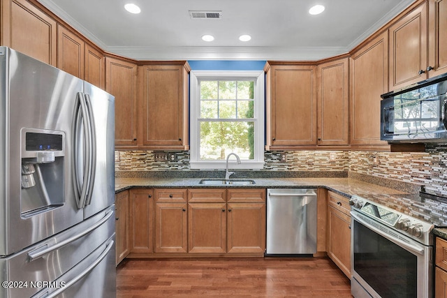 kitchen with dark stone countertops, crown molding, sink, and stainless steel appliances