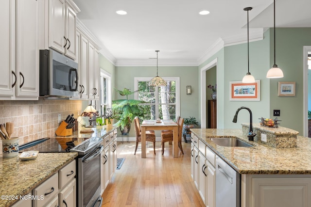 kitchen with stainless steel appliances, white cabinetry, a kitchen island with sink, and sink