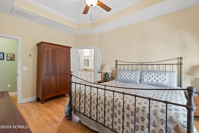 bedroom featuring ornamental molding, ceiling fan, light hardwood / wood-style flooring, and ensuite bath