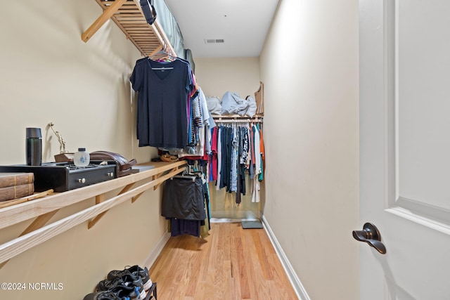 walk in closet with light hardwood / wood-style flooring