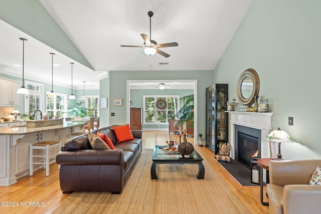 living room featuring light wood-type flooring, lofted ceiling, ceiling fan, and a healthy amount of sunlight